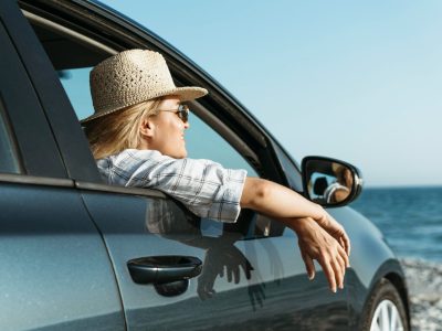 blonde-woman-looking-out-car-window-looking-sea (1)
