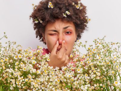 woman-has-problems-with-breathing-holds-nose-suffers-from-allergy-camomile-holds-big-bouquet-flowers-has-red-itchy-eyes (1)